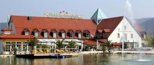 a large building with a red roof on a body of water at Fichtelgebirgshof in Himmelkron