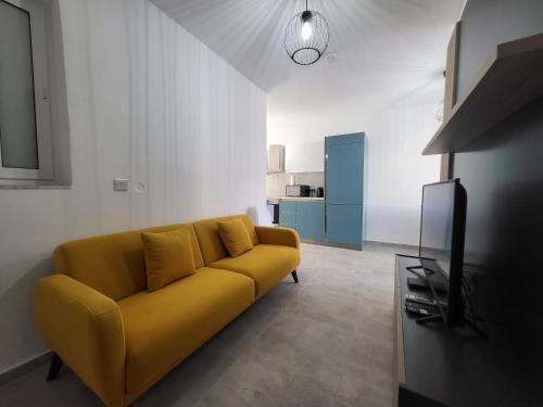 a yellow couch in a living room with a tv at St Julian Apartments in St Julian's