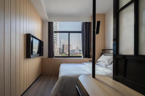 une chambre d'hôtel avec un lit et une fenêtre dans l'établissement Hangzhou Desti Youth Park Hostel, à Hangzhou