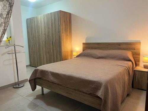 1 dormitorio con 1 cama grande y armario de madera en Modern Apartment in Marsaskala, en Marsaskala