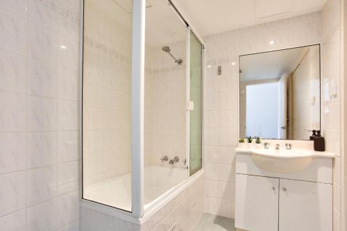 a white bathroom with a shower and a sink at Cozy 2 Bedroom Apartment Surry Hills in Sydney