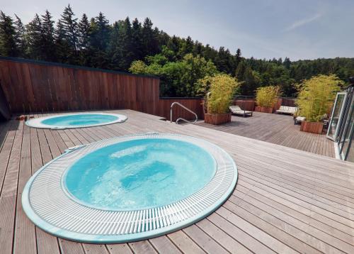 a large swimming pool on a deck with a wooden deck at Boutique Hotel Dobrna - Terme Dobrna in Dobrna