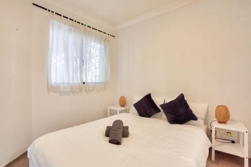 a white bedroom with two beds and a window at Cozy 2 Bedroom Apartment Surry Hills in Sydney