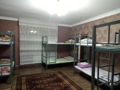a room with three bunk beds and a rug at Азия Hotel in Taraz