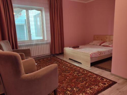 a bedroom with a bed and chairs and a window at Азия Hotel in Taraz