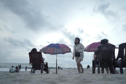 een vrouw op een strand met stoelen en parasols bij Marari Red Angel in Mararikulam