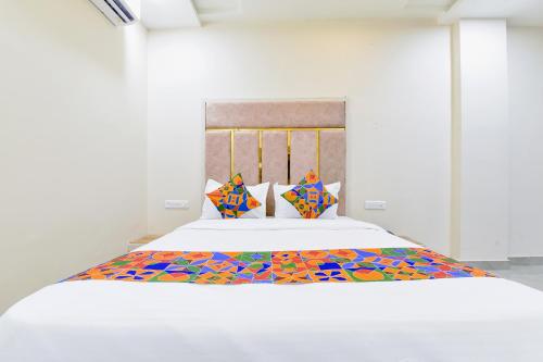 a bedroom with a white bed with colorful sheets and pillows at FabHotel Bohra International in Jaipur