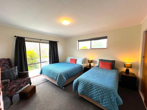 um quarto com 2 camas, uma cadeira e uma janela em Parkview Holiday Home "Opposite of Famous Kuirau Park" em Rotorua