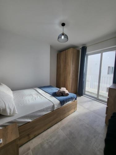 - une chambre avec un lit et une grande fenêtre dans l'établissement St Julian Apartments, à San Ġiljan