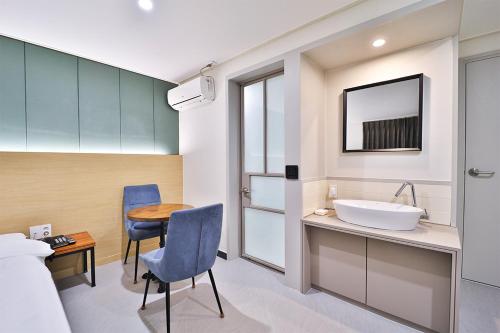 a bathroom with a sink and a table and chairs at Calm Rest Hotel Busan Sasang in Busan