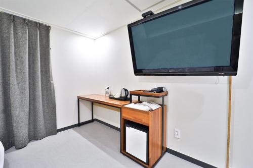 a room with a desk with a large flat screen tv at Calm Rest Hotel Busan Sasang in Busan
