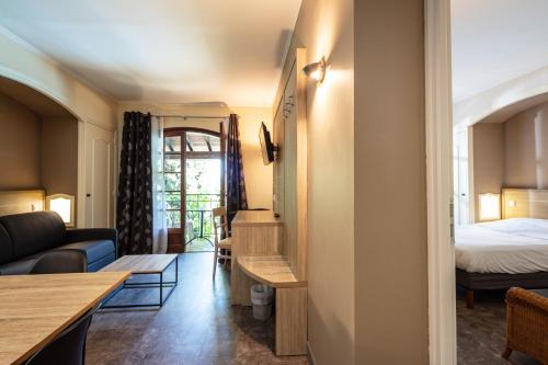een woonkamer met een bank en een bed bij Auberge de la Tour -Appartements- in Valros