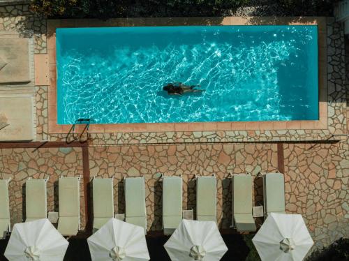 a group of white umbrellas in front of a swimming pool at Dracos Hotel in Parga