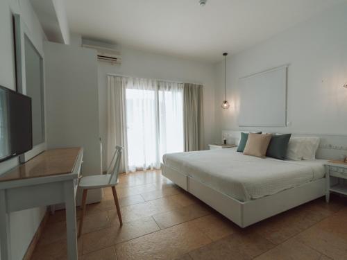 a bedroom with a bed and a desk and a television at Dracos Hotel in Parga