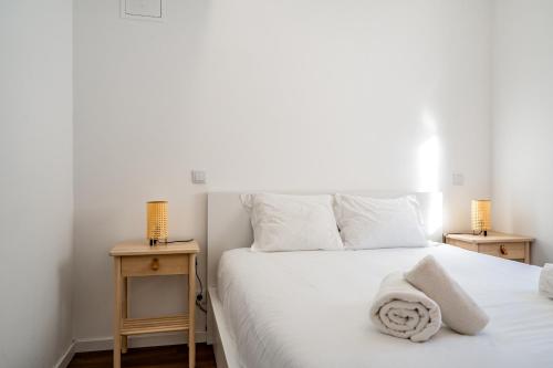 Almada Cityscape Apartment في ألمادا: غرفة نوم بسرير ابيض مع مواقف ليلتين