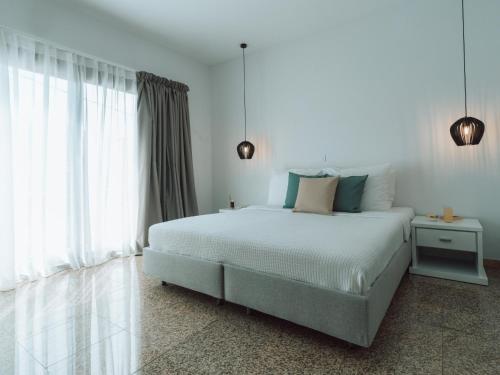 a white bedroom with a bed and a window at Dracos Hotel in Parga