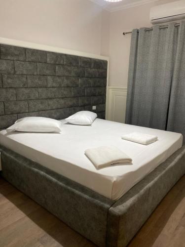 a bedroom with a large bed with white sheets and pillows at Apple Red Hotel in Fier