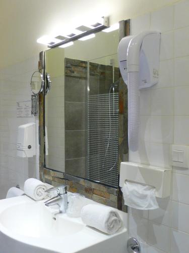 a bathroom with a sink with a shower and a mirror at Logis Hôtel Restaurant le Printania in Dinard