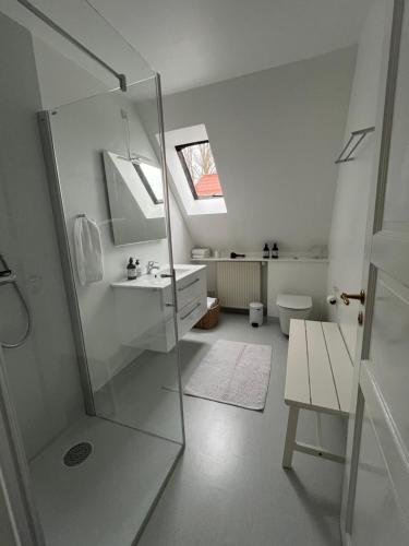 a white bathroom with a shower and a sink at Tåning Gl. Mejeri in Skanderborg