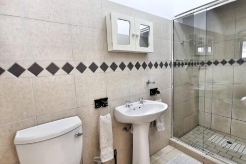 Un baño con inodoro, lavabo y ducha. en Manzini Chalet 39, en St Lucia