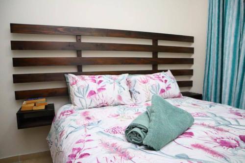 Una cama con cabecero de madera y una almohada verde. en Manzini Chalet 39, en St Lucia