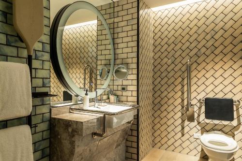 a bathroom with a sink and a mirror and a toilet at Hotel Indigo Taipei North by IHG in Taipei