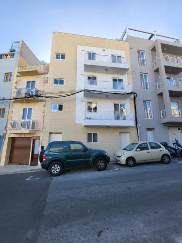 two cars parked in a parking lot in front of a building at St Julian Apartments in St Julian's