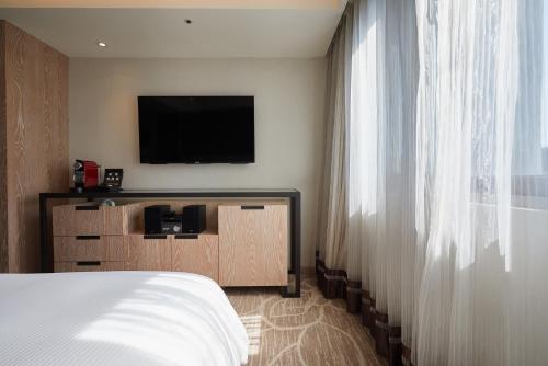 a hotel room with a bed and a flat screen tv at K Hotel Taipei Chang-An in Taipei