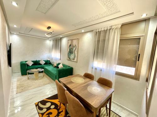 uma sala de estar com uma mesa e um sofá verde em A2 Appartement entièrement neuf au cœur de Témara em Temara
