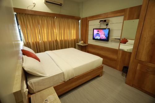 ein Schlafzimmer mit einem Bett und einem TV. in der Unterkunft Haksons Residency in Mananthavady