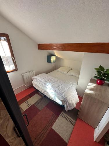 een kleine slaapkamer met een bed en een raam bij Appartement de 32m² au cœur de la Joue du Loup in Le Dévoluy