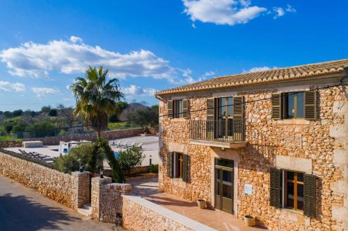 a stone building with a palm tree in front of it at Villa S`Alzina by Slow Villas in Santanyi
