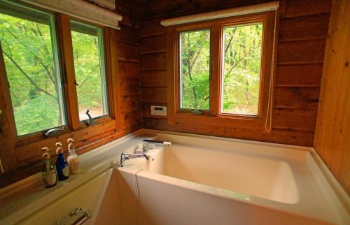 una vasca da bagno in una cabina con due finestre di HARUNA LODGE Private log house with starry sky from the skylight, fireplace, and spacious deck BBQ a Nasu