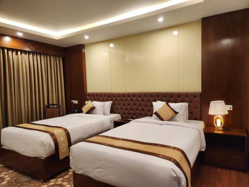 a hotel room with two beds and a lamp at Paragon Hotel and Resort in Sreemangal