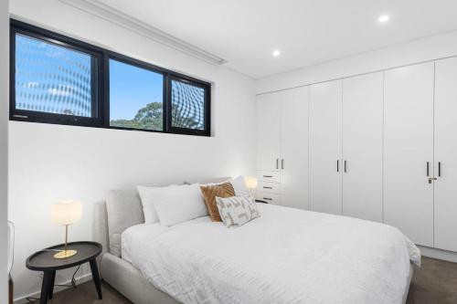 a white bedroom with a bed and a couch at Addison's Escape - A Breezy Beachfront Beauty in Shellharbour