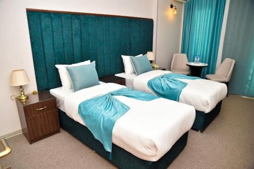 two beds in a hotel room with blue walls at Karat Inn Boutique Hotel in Baku