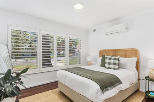 a bedroom with a large bed and windows at Surfside Escape - A Local Lifestyle at North Beach in Wollongong