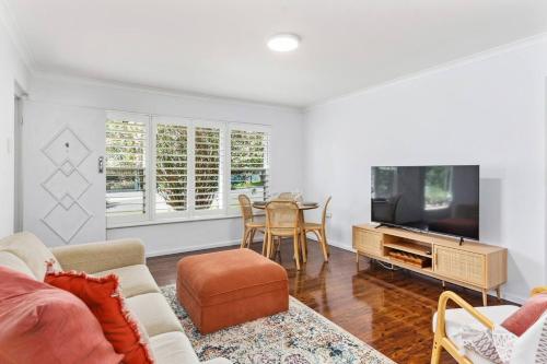 a living room with a couch and a tv and a table at Surfside Escape - A Local Lifestyle at North Beach in Wollongong