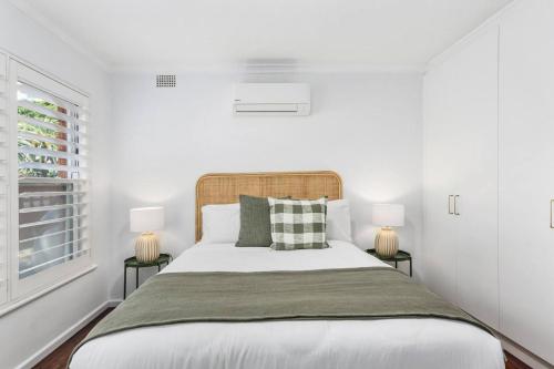 a white bedroom with a bed with two lamps at Surfside Escape - A Local Lifestyle at North Beach in Gwynneville