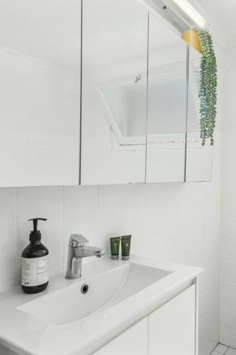 a white bathroom with a sink and a mirror at Surfside Escape - A Local Lifestyle at North Beach in Wollongong