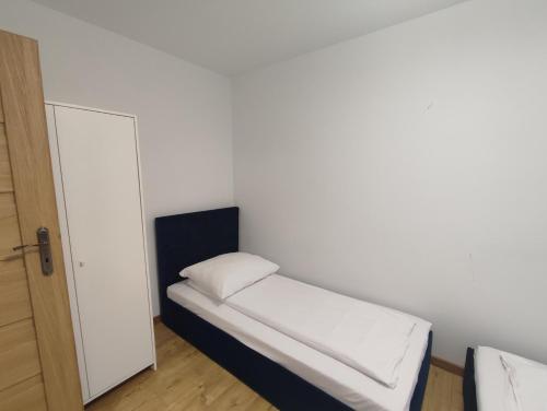 een kleine kamer met een klein wit bed met een deur bij Mieszkanie ul. Raciborskiego in Mielec