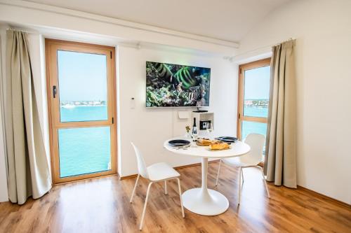 a white table and chairs in a room with windows at Umag apartment center seafront seaview old town 2 in Umag