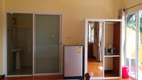 Cette chambre dispose d'un réfrigérateur blanc et d'une porte en verre. dans l'établissement เขาหลัก ซัมเมอร์เฮาส์ 2, à Khao Lak