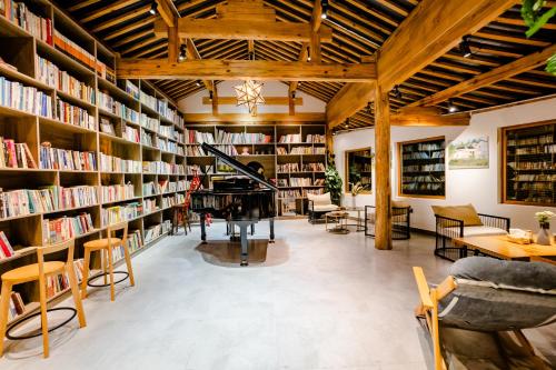 a library with lots of bookshelves and a piano at Lijiang One House Designer Guesthouse in Lijiang