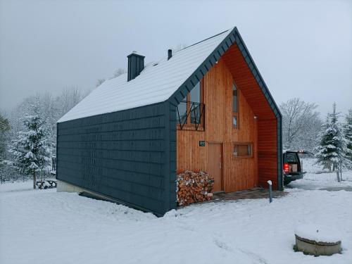 a wooden cabin with a gambrel roof in the snow at Czarna Chata in Jaworzynka