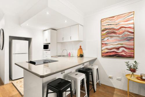 une cuisine avec des placards blancs et un îlot de cuisine avec des tabourets dans l'établissement 4mins to Darling Hrbr! 1 BD+Park, à Sydney