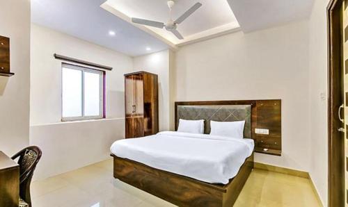 a bedroom with a bed and a desk and a window at FabExpress Mohan Vilas Residency in Dehradun