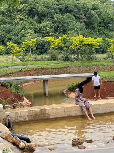a man sitting on a ledge in the water at Maryland Khaoyai Annapolis Pool Villa in Ban Nong Song Hong