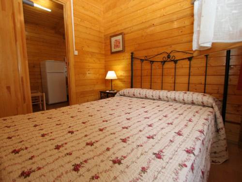 ein Schlafzimmer mit einem großen Bett in einem Holzzimmer in der Unterkunft Bungalows Costa San Juan in Soto de la Marina