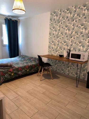 sypialnia z łóżkiem i stołem z kuchenką mikrofalową w obiekcie Studio cosy - Sainte-Clotilde w mieście Saint-Denis